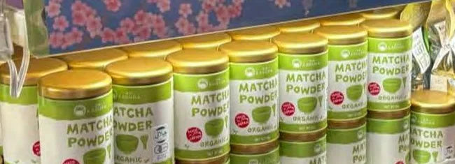 Rows of KAGURA Matcha Powder tins on the shelf at a Don Quijote store in Shinjuku, Tokyo
